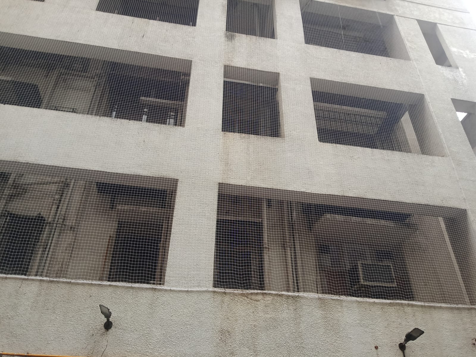 Bird netting covering balcony openings on a multi-storey building